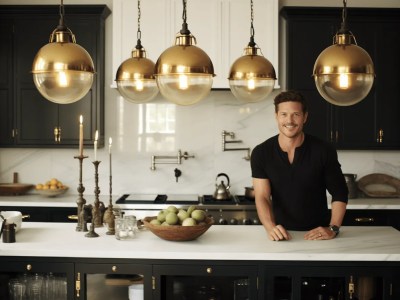 Man Standing In Front Of A Black Kitchen With White Pendant Lights